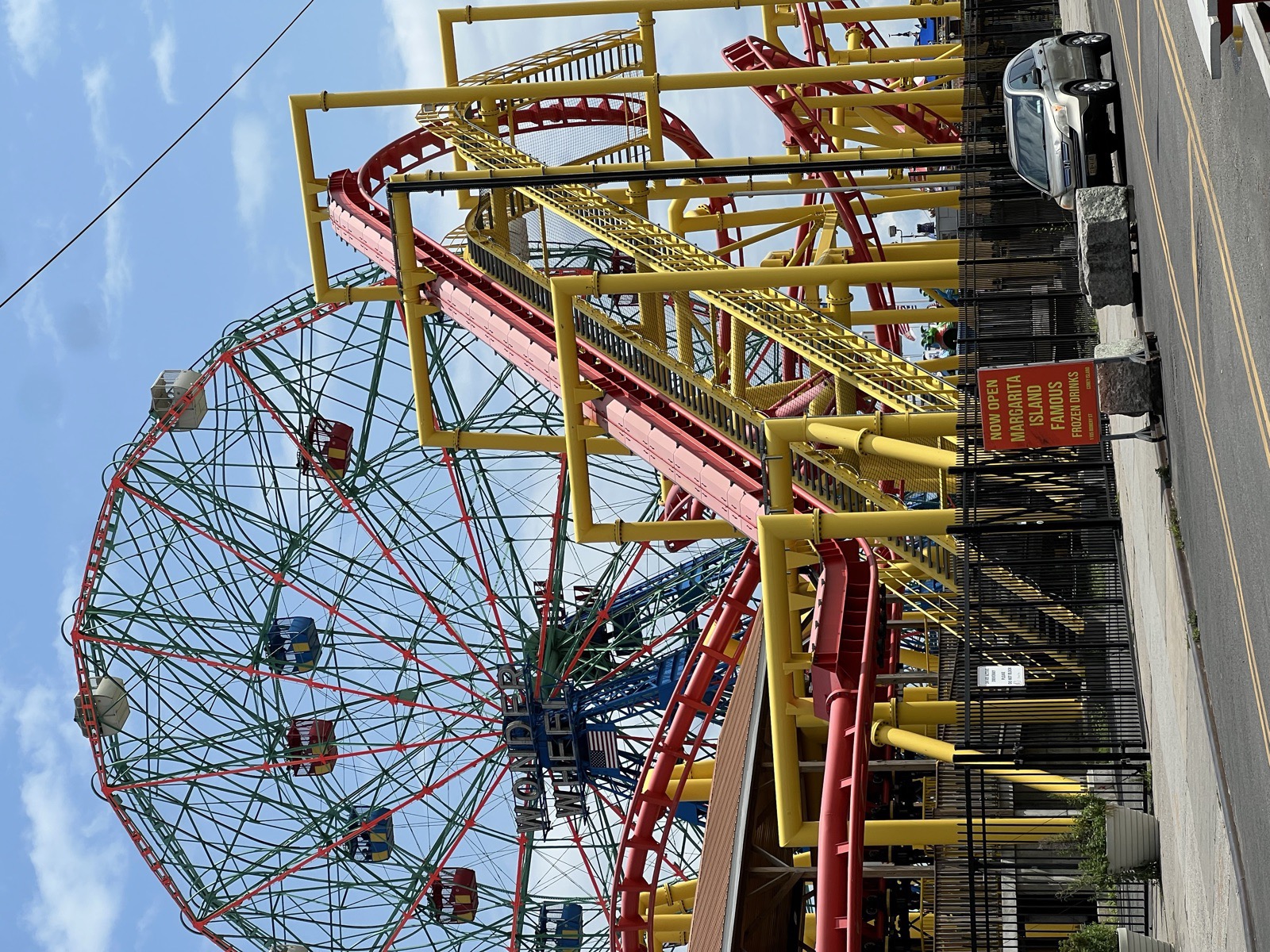 The Wonder Wheel behind the coaster tracks at Coney Island, summer sky above