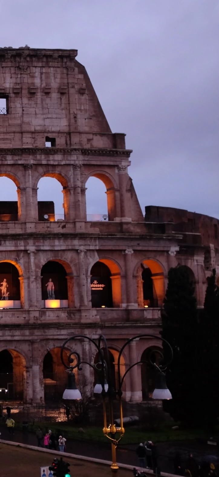 The Colosseum at dusk, arches glowing from inside